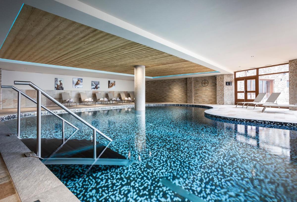 une piscine avec de l'eau bleue dans un immeuble dans l'établissement Résidence Daria-I Nor by les Etincelles, à L'Alpe-d'Huez