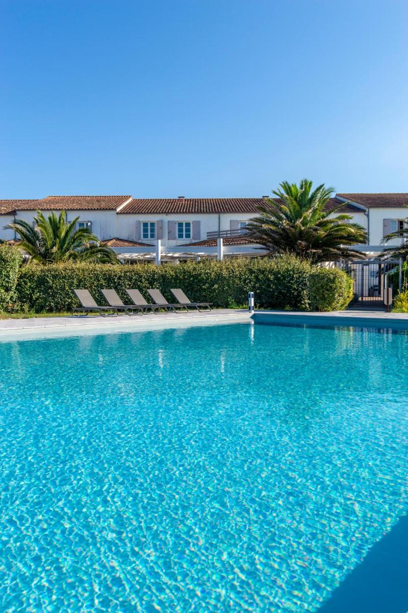 une grande piscine bleue avec des chaises et un bâtiment dans l'établissement Thalacap Île de Ré - Thalasso & Spa, à Ars-en-Ré