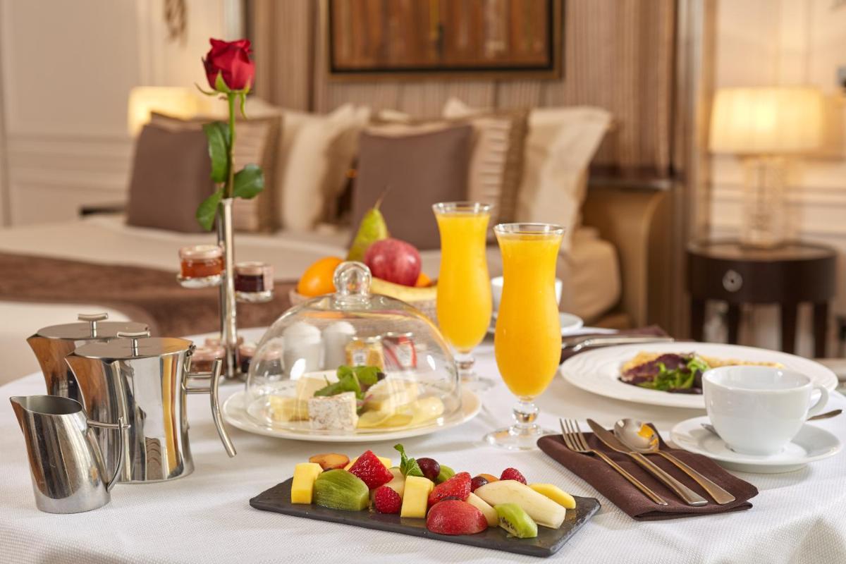 une table avec une assiette de nourriture et du jus d'orange dans l'établissement Majestic Apartments Champs Elysées, à Paris