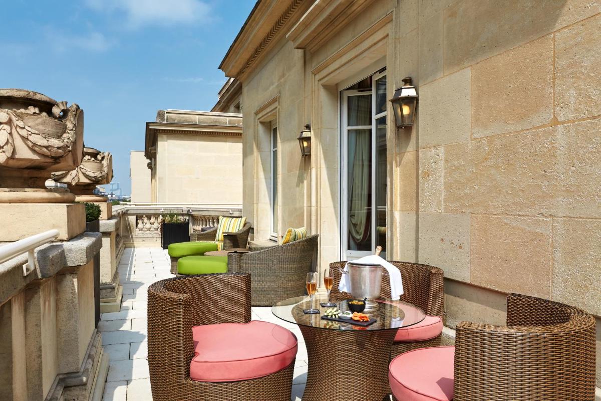 d'une terrasse avec des chaises et des tables en osier sur un balcon. dans l'établissement Majestic Apartments Champs Elysées, à Paris