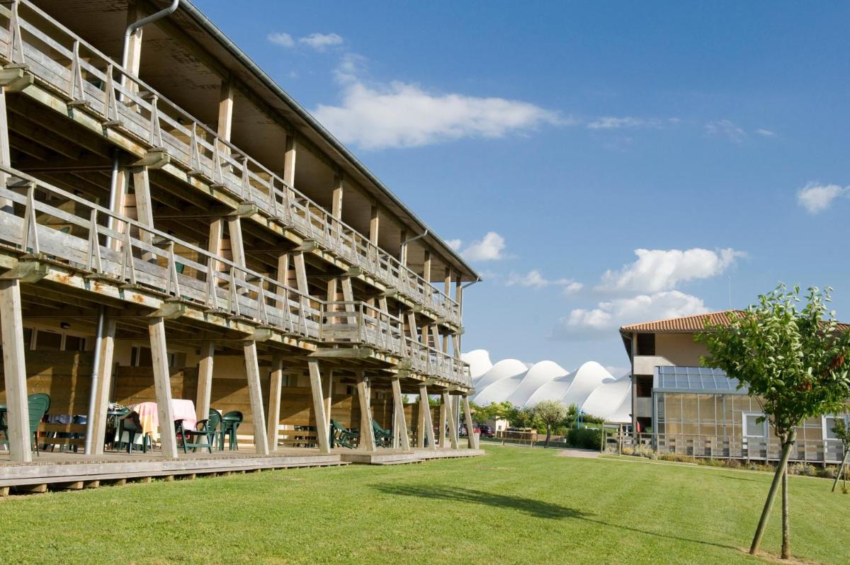 un grand bâtiment avec des tables et des chaises dans un champ dans l'établissement Résidence Pierre & Vacances Les Rives de la Seugne, à Jonzac