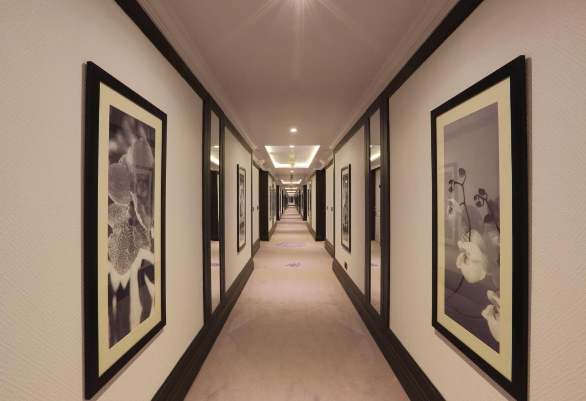 a hallway with framed pictures on the walls at Hotel Royal Orchid Bangalore in Bengaluru