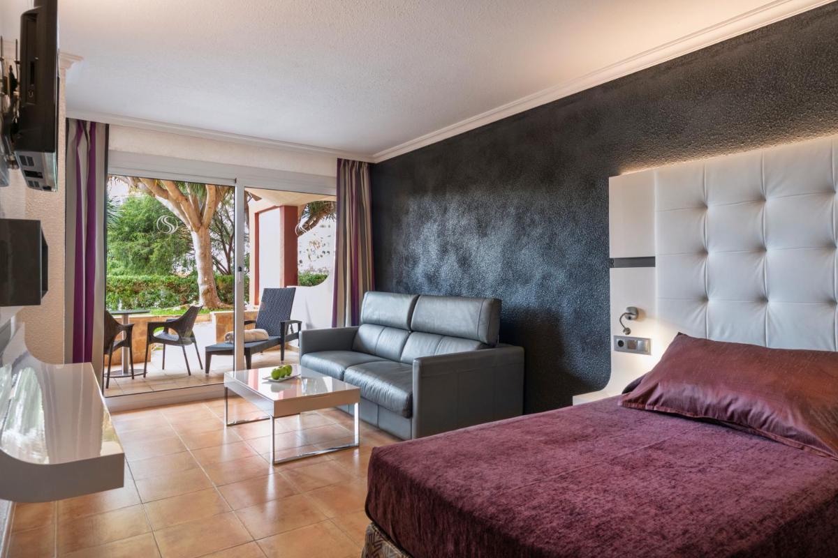Un dormitorio con una cama, un sofá y una mesa. en Salles Hotels Marina Portals, en Portals Nous