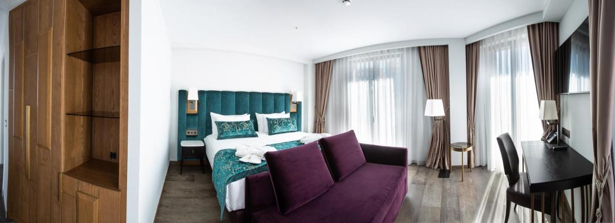 Una habitación de hotel con una cama y un sofá morado. en Boutique Hotel Élke Spa Superior, en Sant Feliu de Guíxols