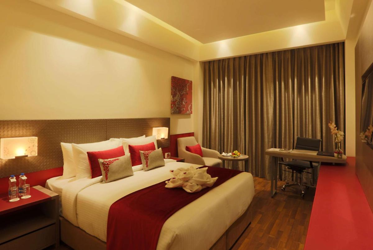 a hotel room with a large bed and a desk at Ramada by Wyndham Lucknow Hotel and Convention Center in Lucknow