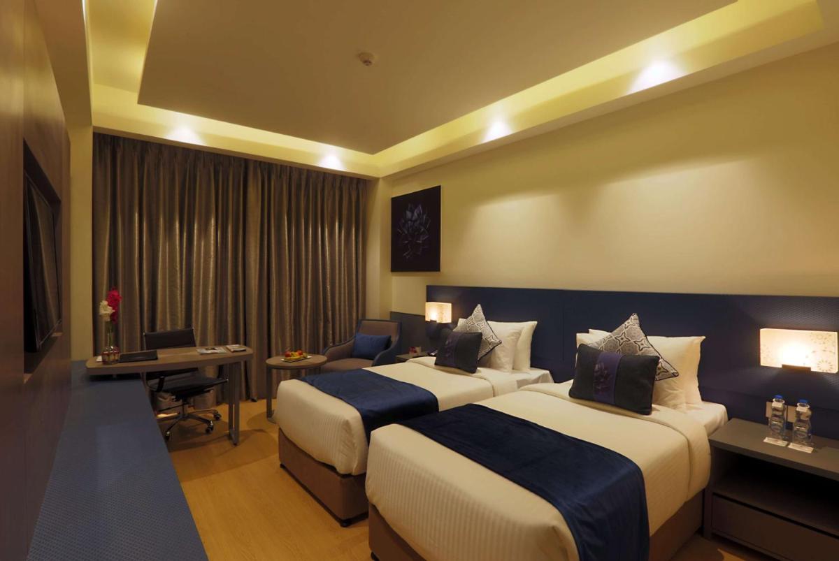 a hotel room with two beds and a desk at Ramada by Wyndham Lucknow Hotel and Convention Center in Lucknow
