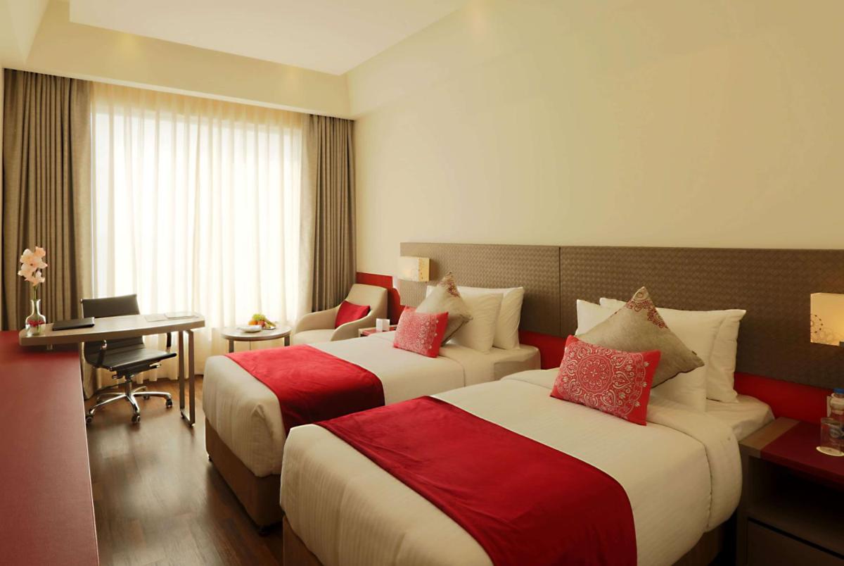 a hotel room with two beds and a desk at Ramada by Wyndham Lucknow Hotel and Convention Center in Lucknow