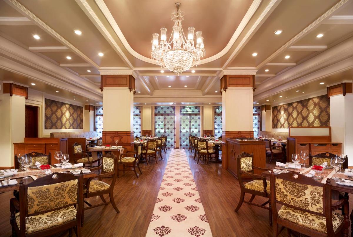 a restaurant with tables and chairs and a chandelier at Taj Ganges Varanasi in Varanasi