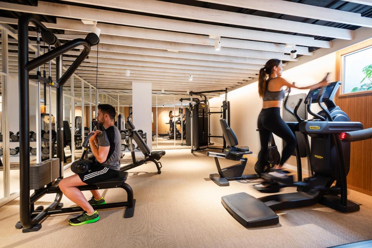 un hombre y una mujer haciendo ejercicio en cintas de correr en un gimnasio en Inturotel Cala Esmeralda Beach Hotel & Spa - Adults Only, en Cala d´Or