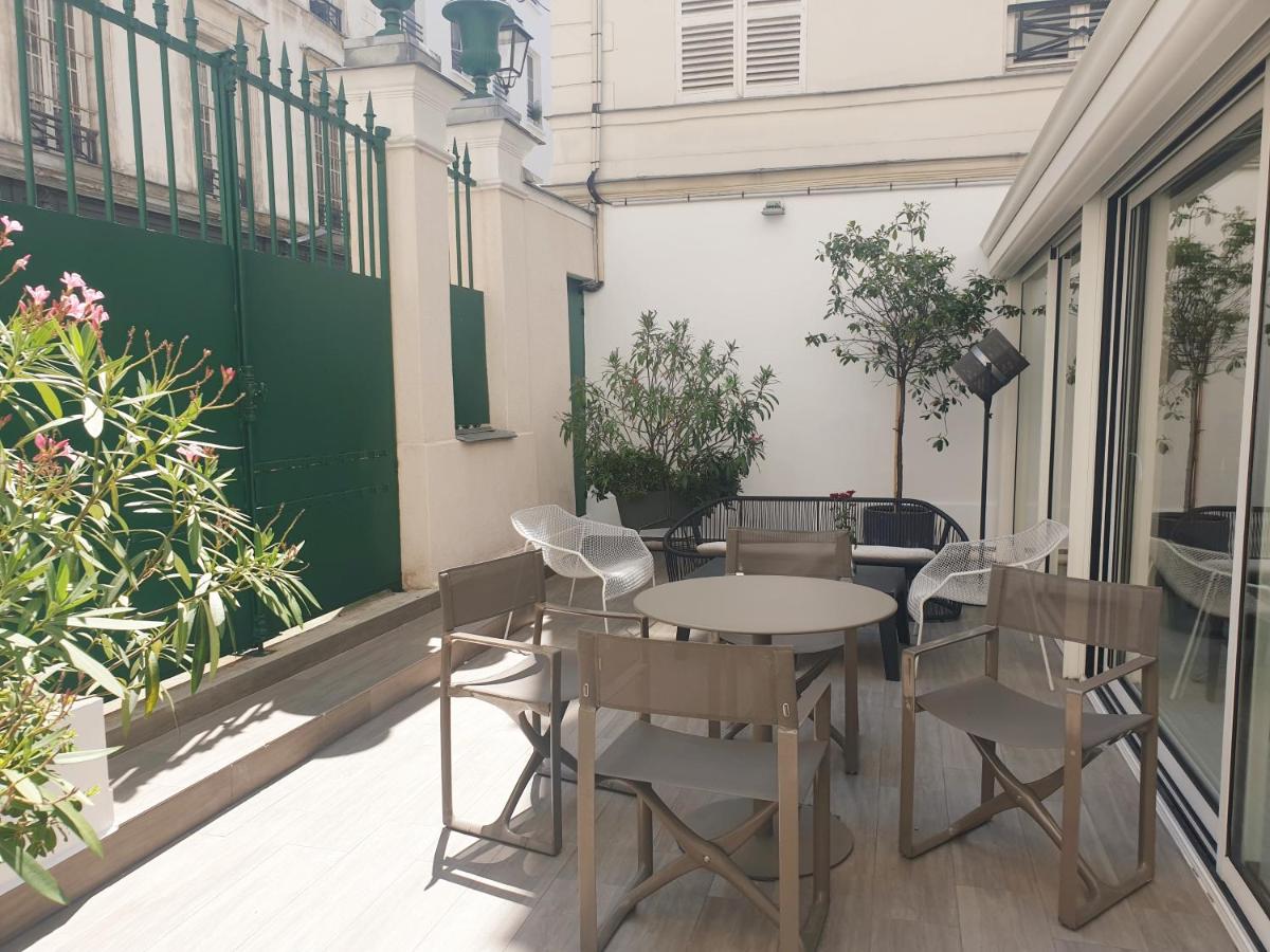 une table et des chaises sur une terrasse avec des plantes dans l'établissement Hôtel Brésil Opéra SPA, à Paris