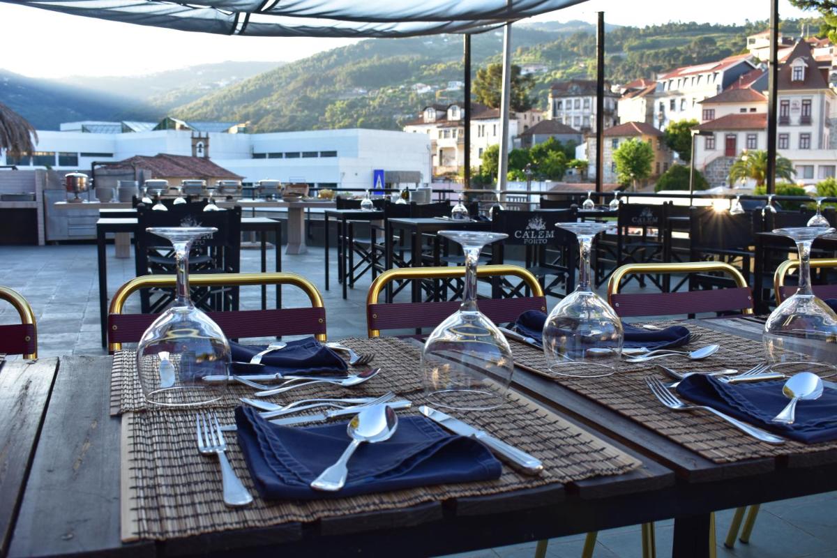 uma mesa de madeira com talheres e copos de vinho em Douro Marina Hotel & SPA em Resende