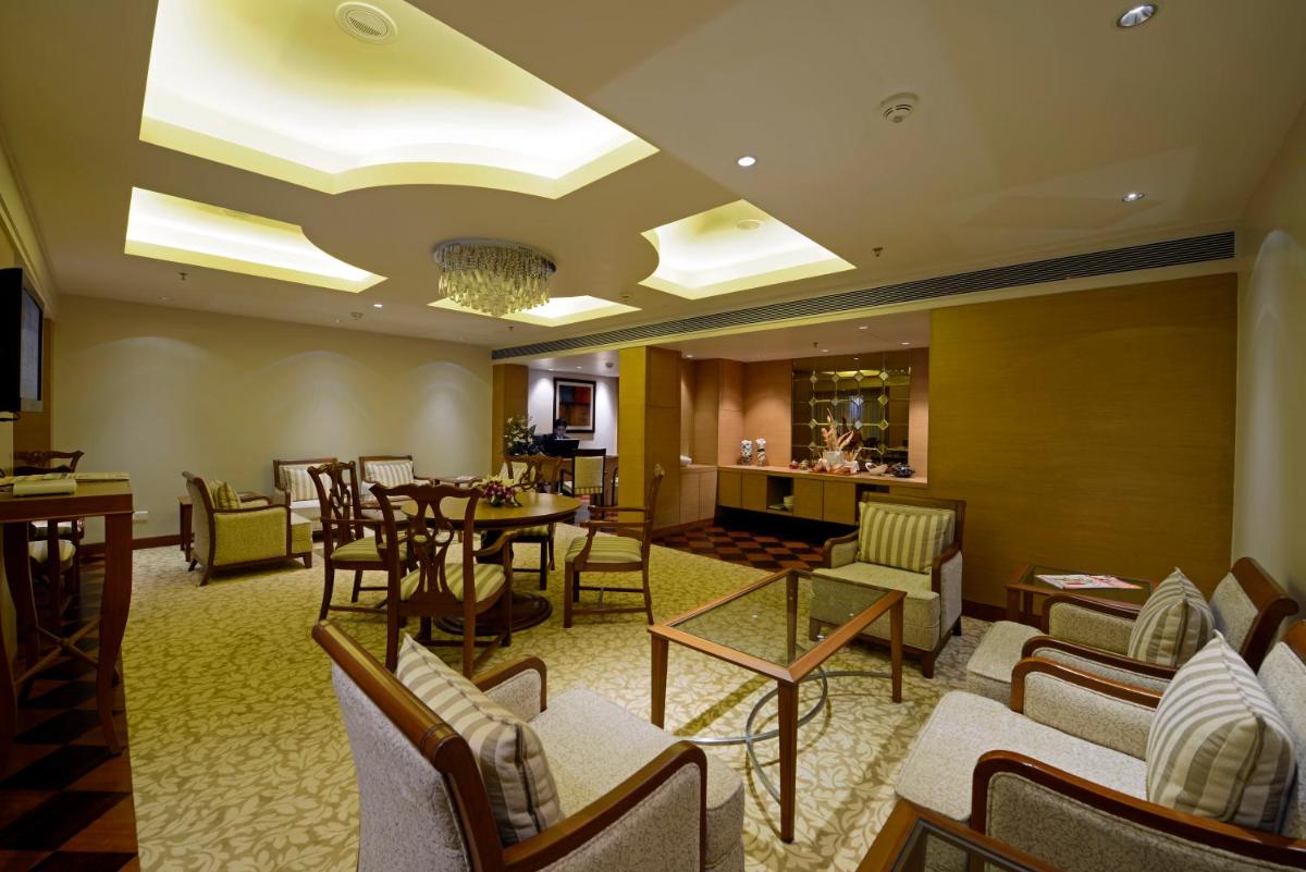 a lobby with chairs and tables and a dining room at Radisson Blu Hotel Ahmedabad in Ahmedabad