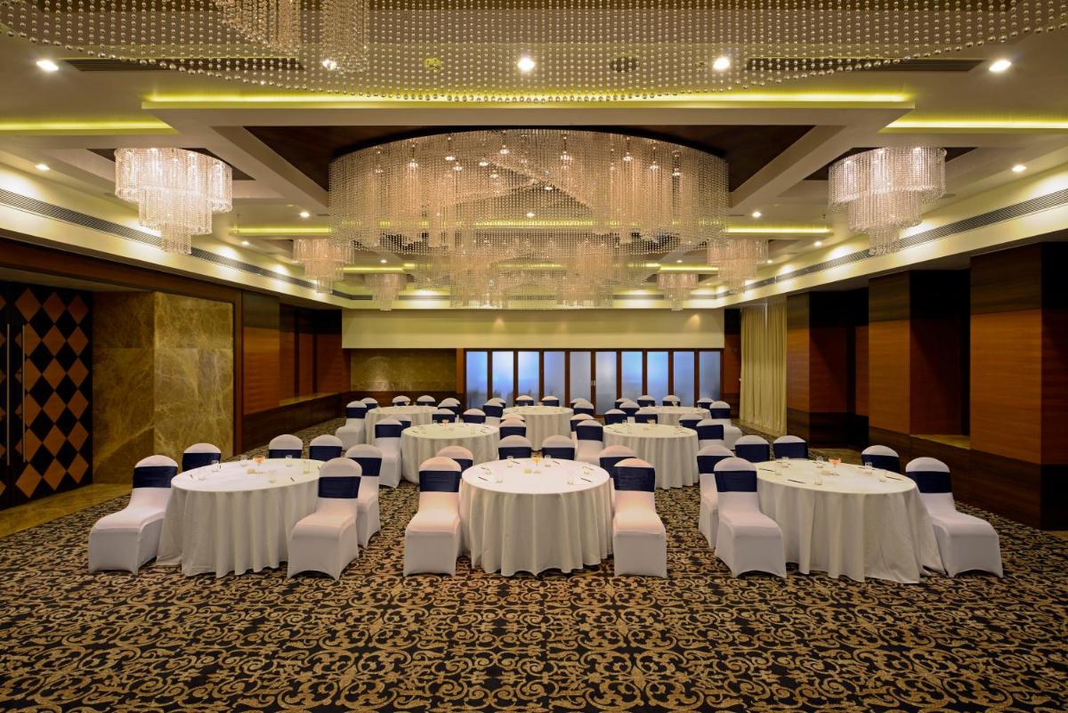 a banquet hall with white tables and chairs and chandeliers at Radisson Blu Hotel Ahmedabad in Ahmedabad