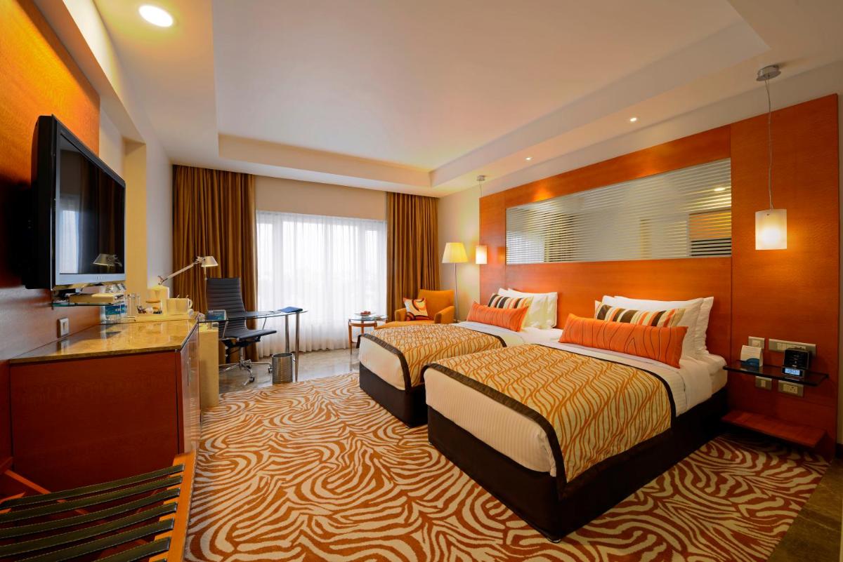 a hotel room with two beds and a flat screen tv at Radisson Blu Hotel Ahmedabad in Ahmedabad