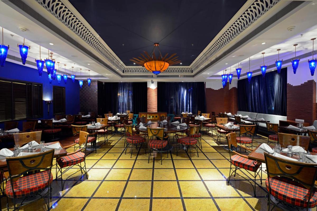a restaurant with tables and chairs in a room at Radisson Blu Hotel Ahmedabad in Ahmedabad