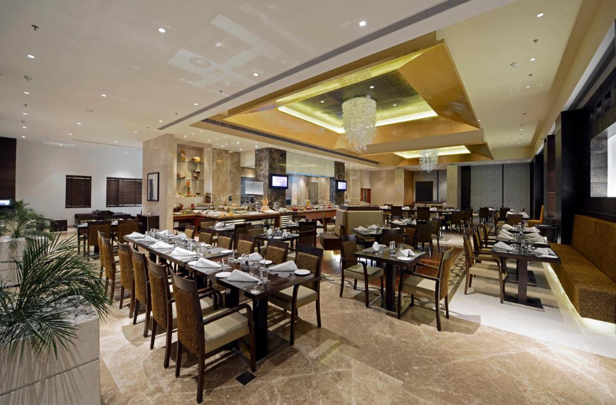 a restaurant with tables and chairs and a bar at Radisson Blu Hotel Ahmedabad in Ahmedabad