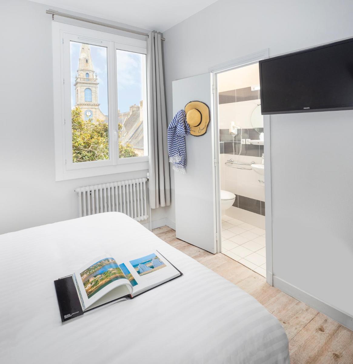 - une chambre avec un lit et une vue sur une église dans l'établissement Hôtel Spa De La Citadelle Lorient, à Port-Louis
