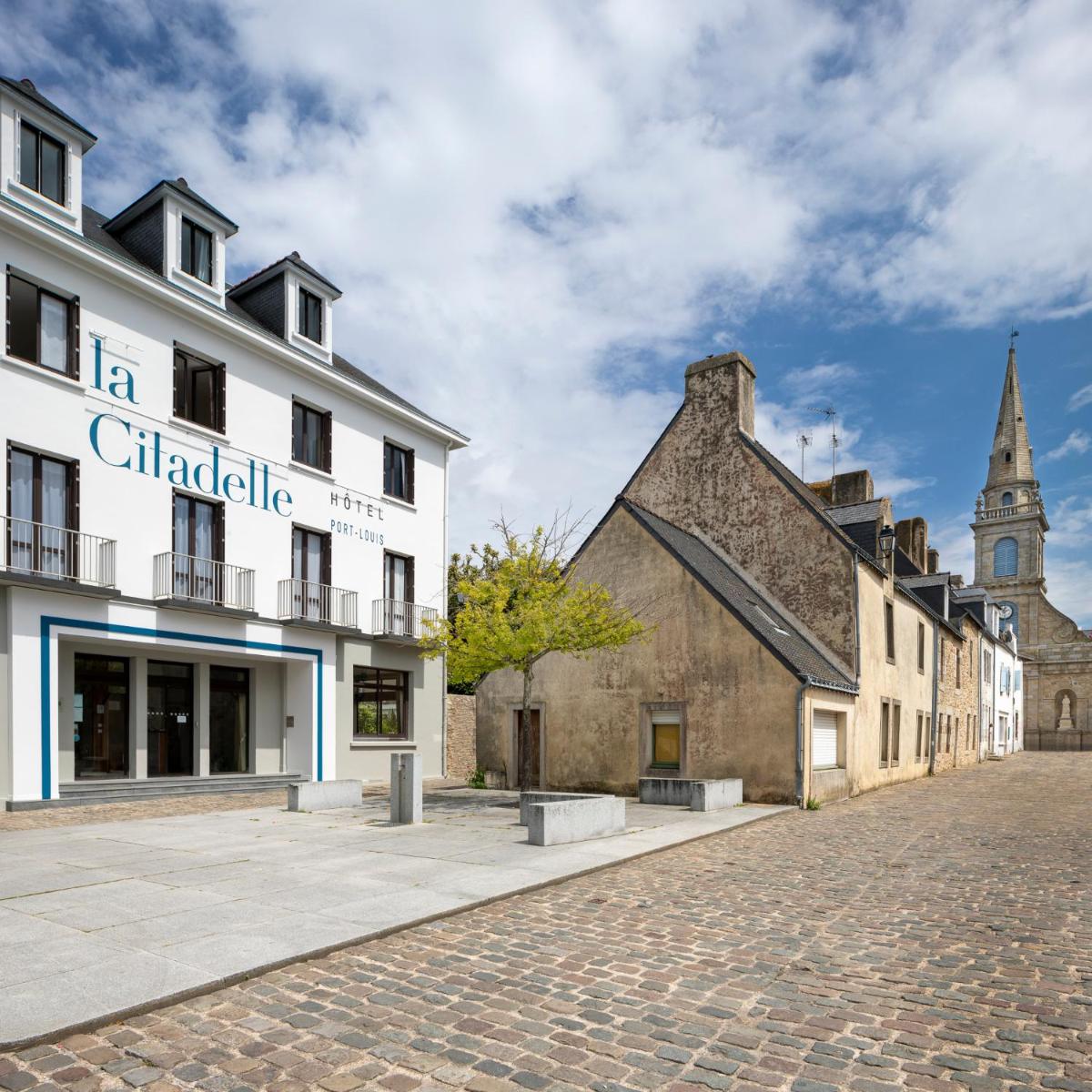 une rue pavée dans une ville avec une église dans l'établissement Hôtel Spa De La Citadelle Lorient, à Port-Louis