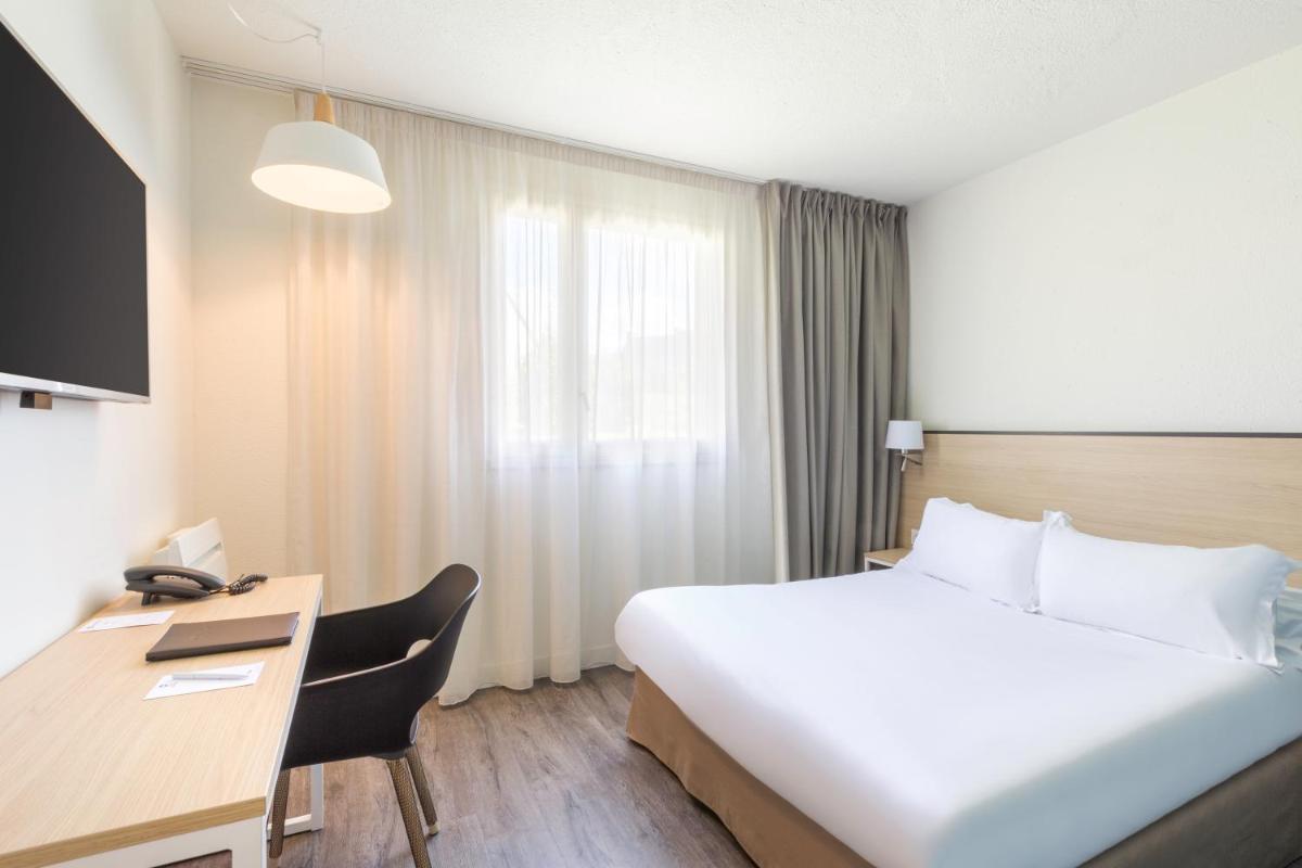 une chambre d'hôtel avec un grand lit et un bureau dans l'établissement Best Western Armor Park Dinan et Spa, à Dinan