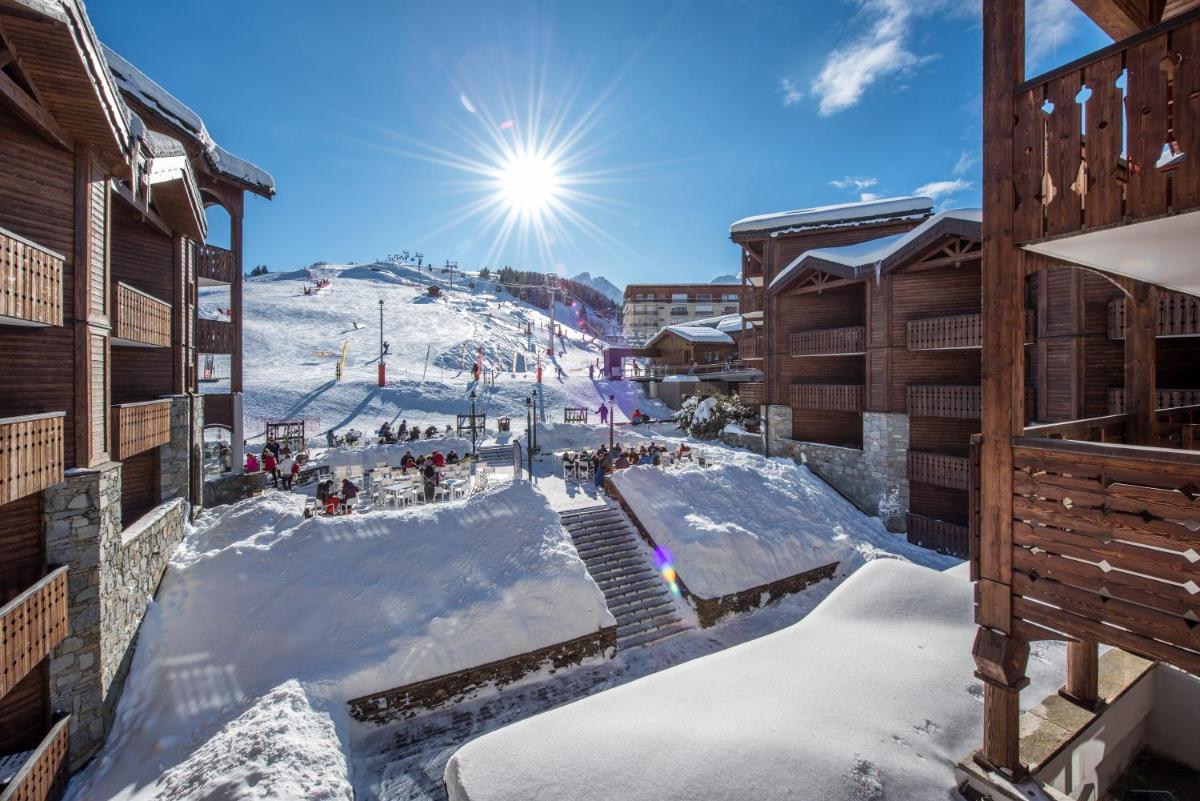 une station de ski avec des bâtiments enneigés et une piste de ski dans l'établissement Fahrenheit Seven Courchevel, à Courchevel