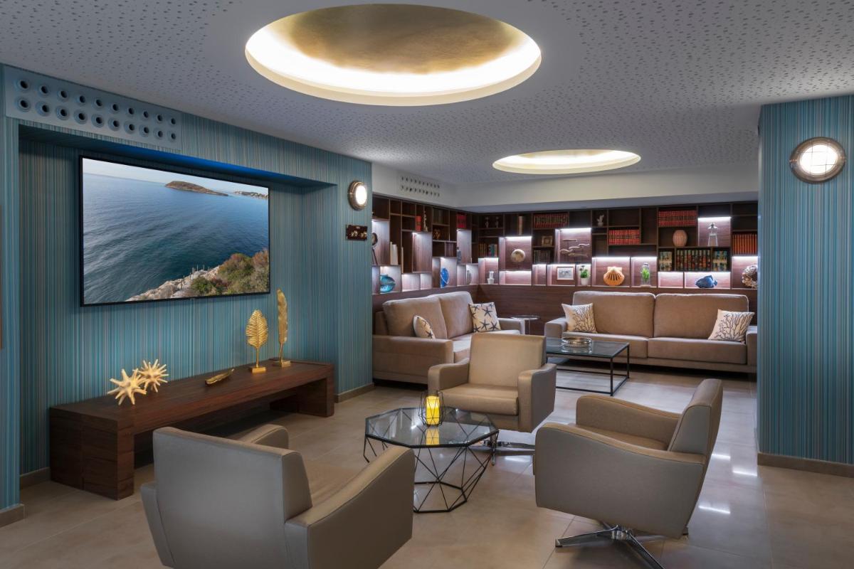 una sala de espera con sofás y TV en la pared en Elba Sunset Mallorca Thalasso Spa, en Palmanova