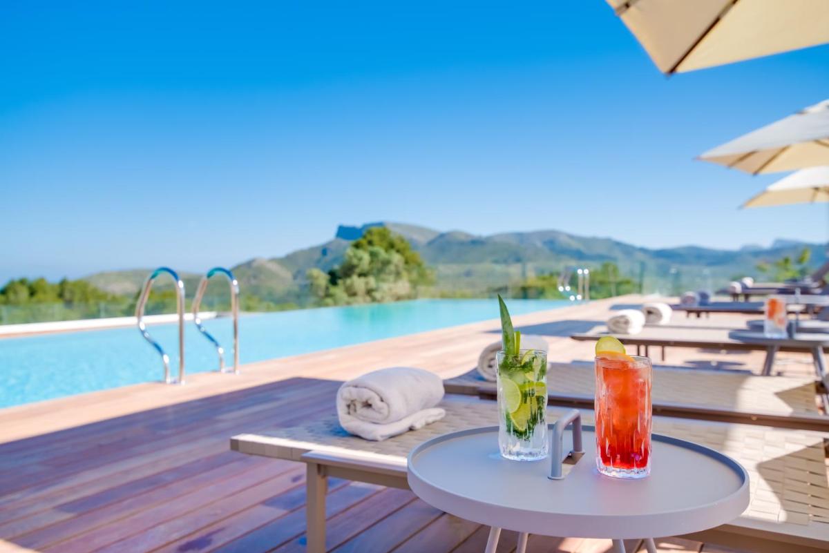 un complejo con una piscina y mesas con bebidas en Carrossa Hotel & Spa, en Artà