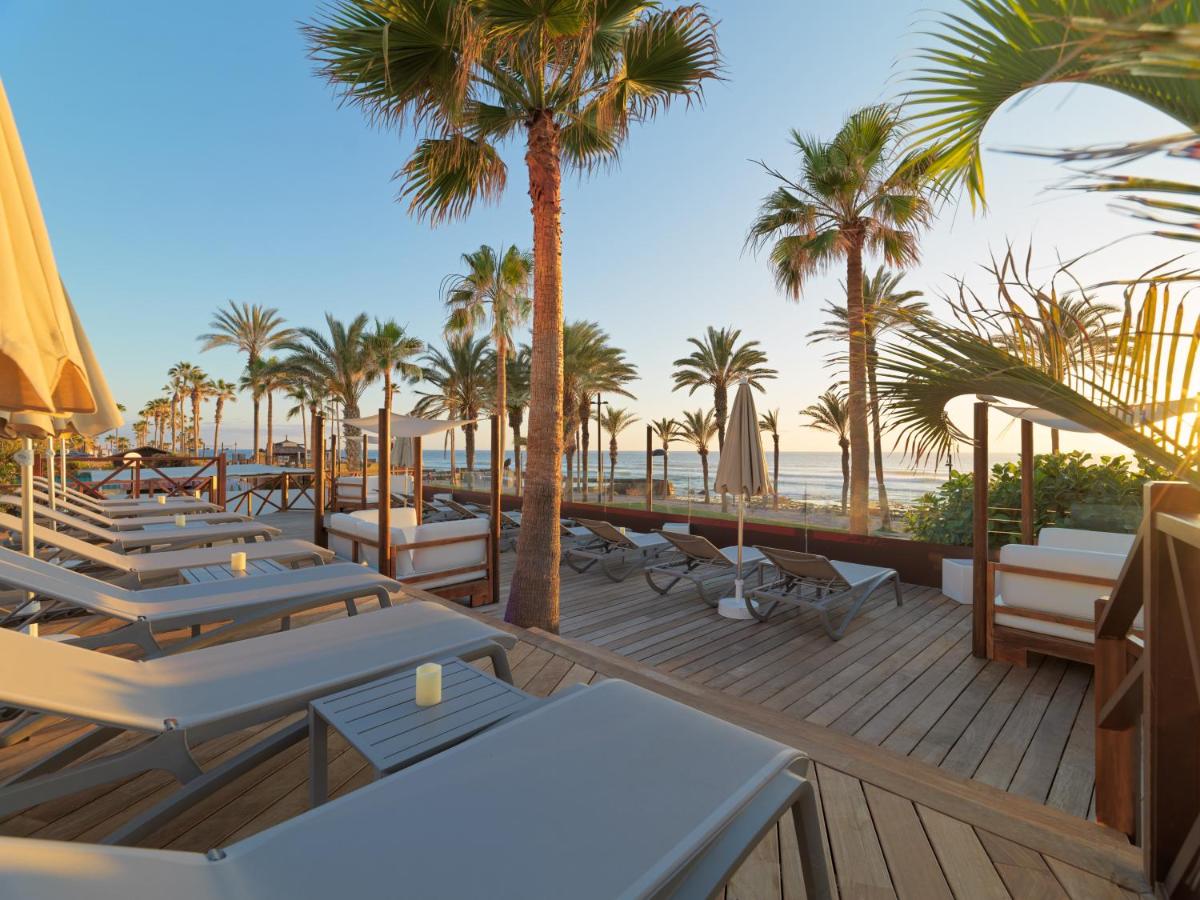 Una fila de mesas y sillas en una terraza con palmeras. en H10 Conquistador, en Playa de las Américas 60 fotos más