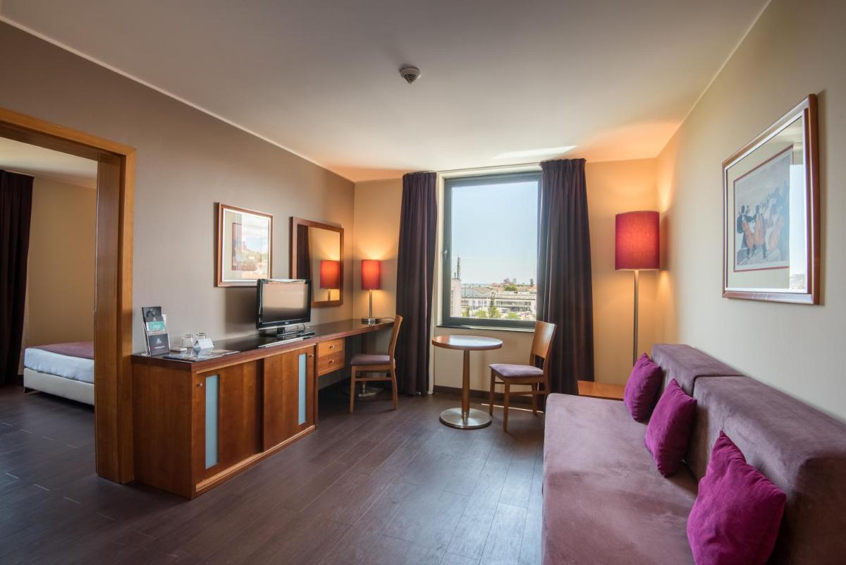 um quarto de hotel com uma cama e uma escrivaninha com uma televisão em Vila Gale Opera em Lisboa