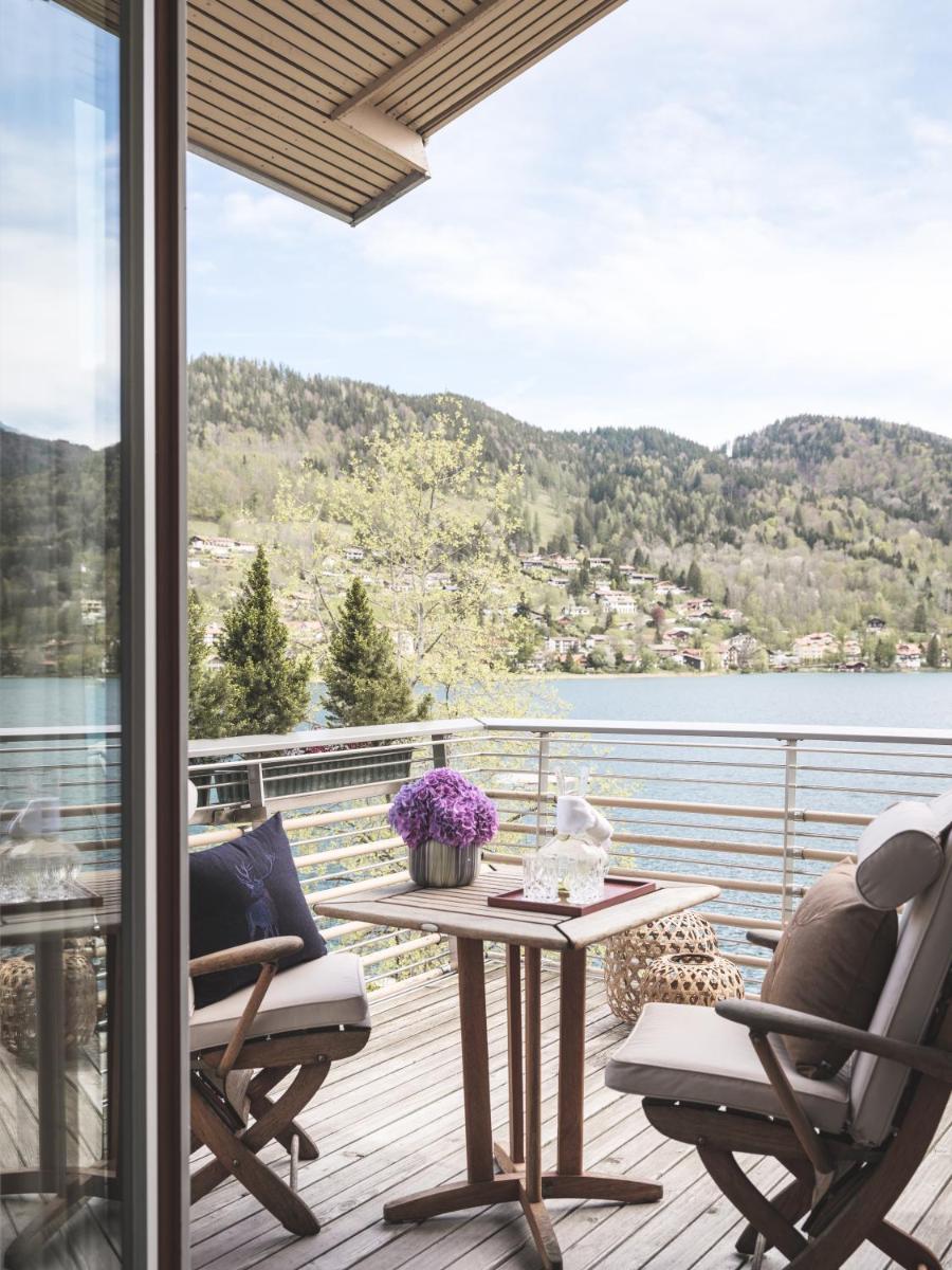 ein Balkon mit Tisch und Stühlen und Blick auf das Wasser in der Unterkunft Althoff Seehotel Überfahrt in Rottach-Egern