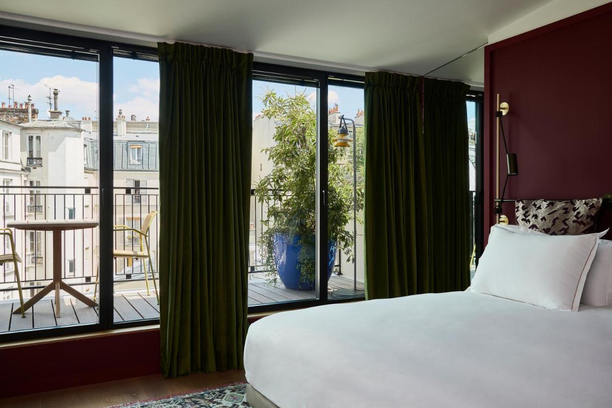 une chambre avec un lit et une grande fenêtre dans l'établissement Hôtel Le Ballu, à Paris une chambre avec un lit et une grande fenêtre dans l'établissement Hôtel Le Ballu, à Paris