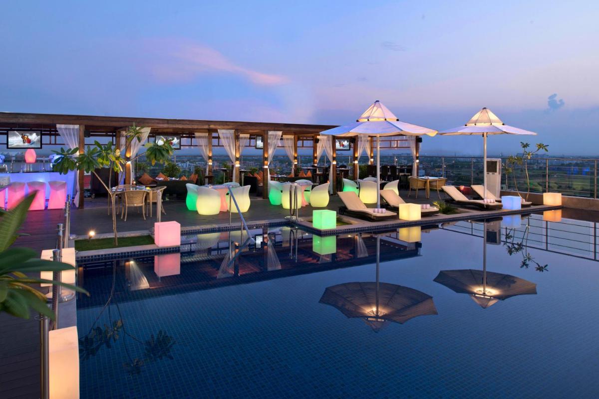 a hotel swimming pool with chairs and umbrellas at Radisson Blu Jaipur in Jaipur