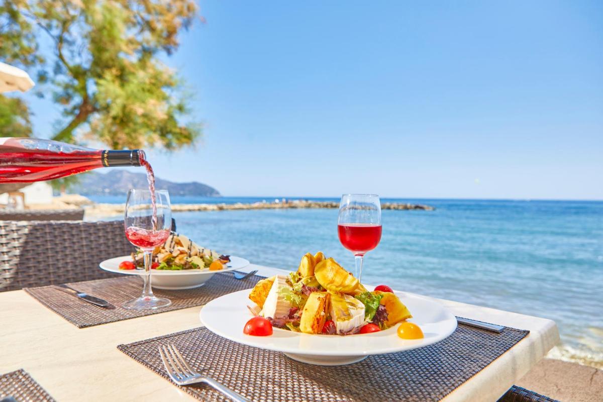 Una mesa con un plato de comida y copas de vino. en Hotel Ilusion Moreyo - Adults Only, en Cala Bona