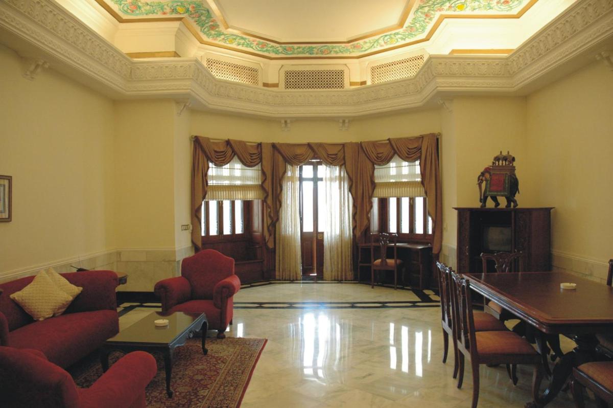 a living room with a couch and a table and chairs at The Lalit Laxmi Vilas Palace in Udaipur