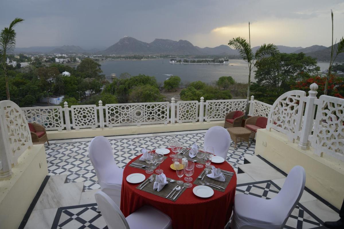 a table and chairs on a balcony with a view at The Lalit Laxmi Vilas Palace in Udaipur