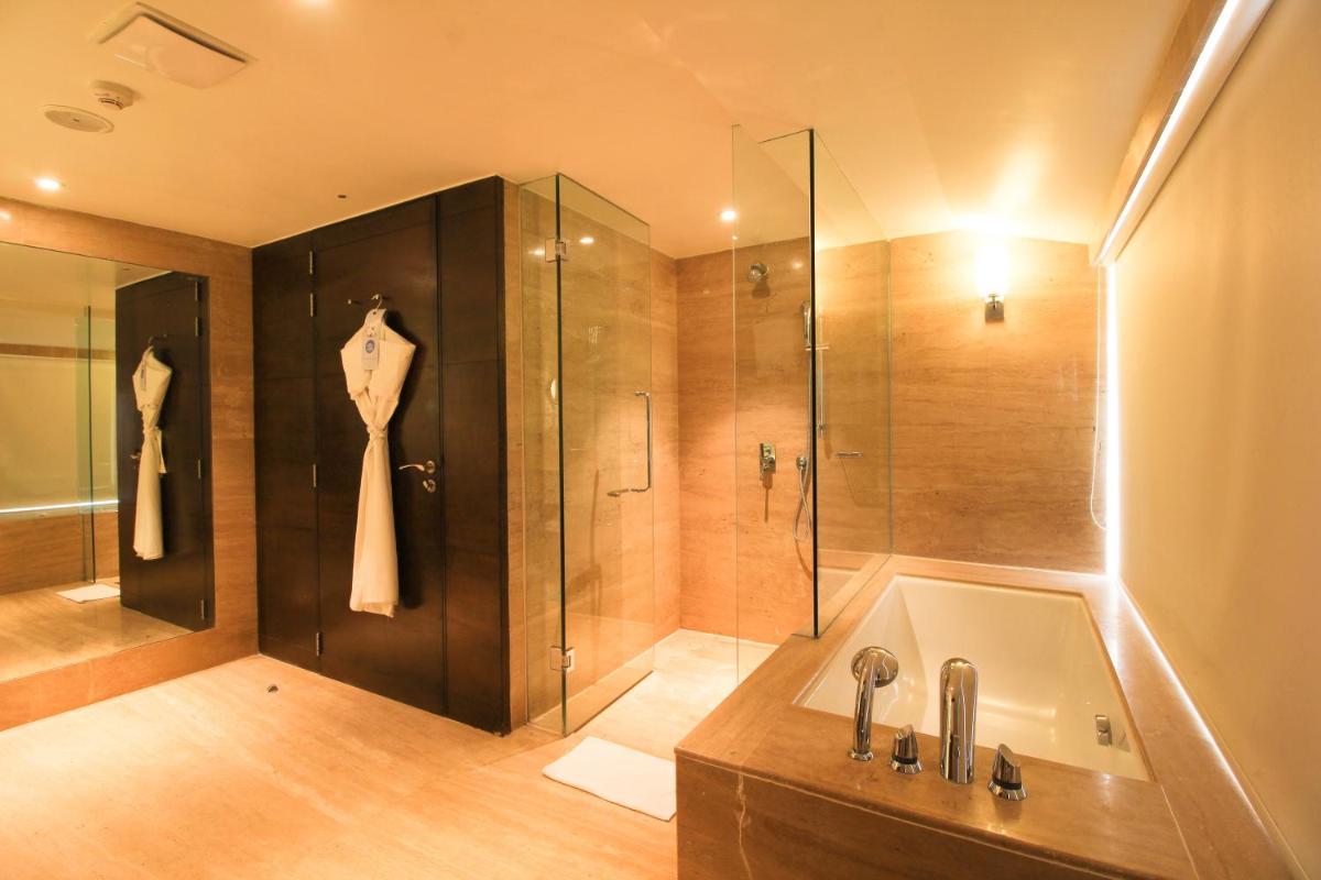 a bathroom with a shower and a tub and a sink at Novotel Goa Candolim in Candolim a bathroom with a shower and a tub and a sink at Novotel Goa Candolim in Candolim