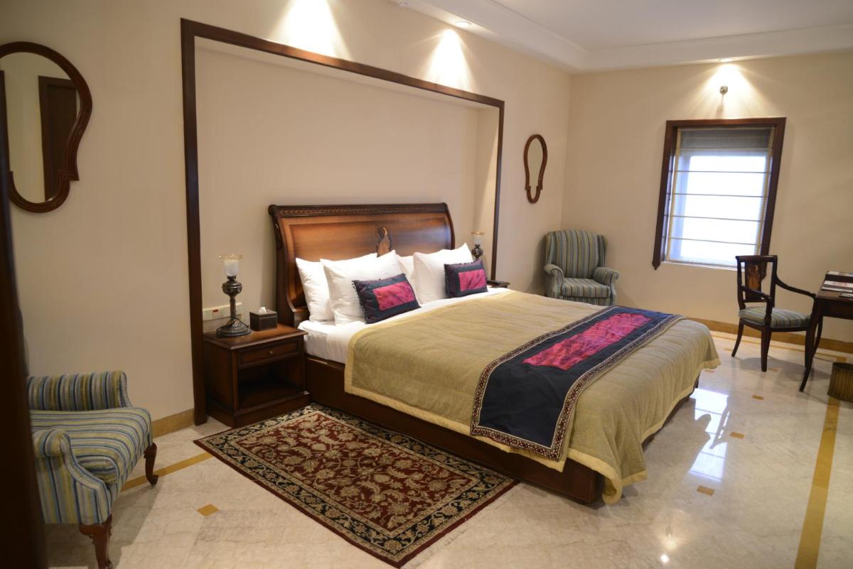 a bedroom with a bed and a table and chairs at The Lalit Laxmi Vilas Palace in Udaipur
