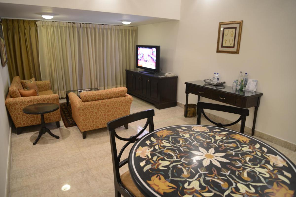a living room with a table and chairs and a television at The Lalit Laxmi Vilas Palace in Udaipur