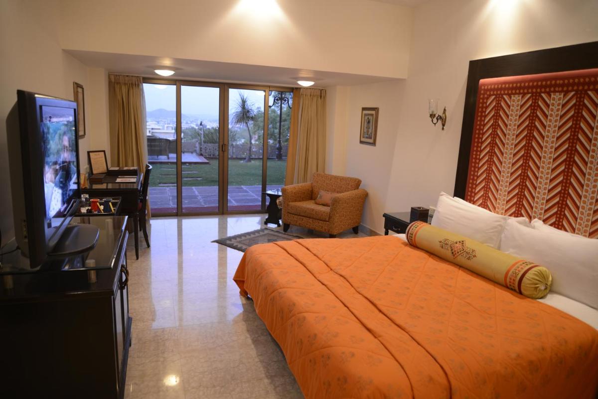 a hotel room with a bed and a television at The Lalit Laxmi Vilas Palace in Udaipur