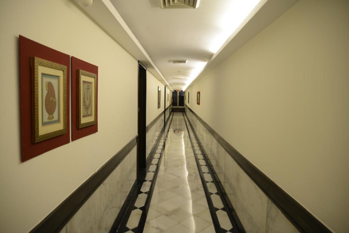 an empty hallway in a building with paintings on the walls at The Lalit Laxmi Vilas Palace in Udaipur