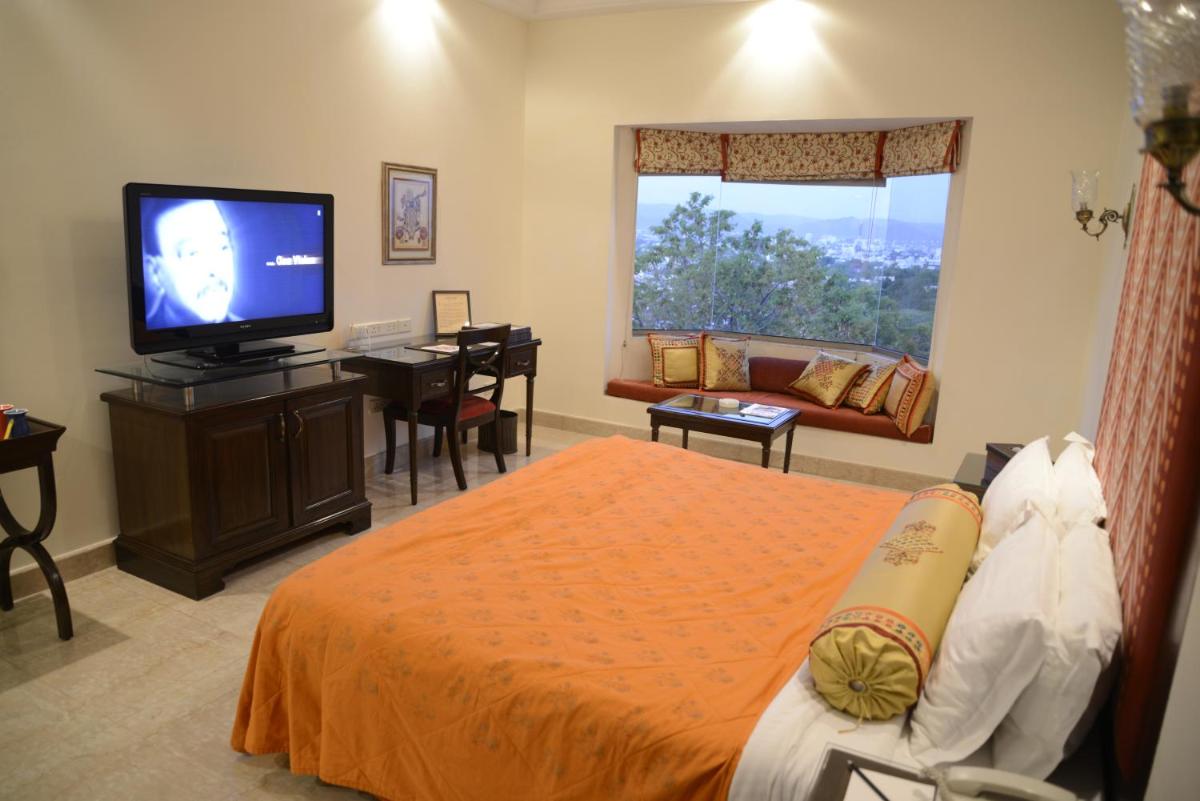a bedroom with a bed and a tv and a couch at The Lalit Laxmi Vilas Palace in Udaipur