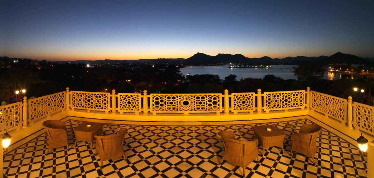 a balcony with chairs and a view of the water at The Lalit Laxmi Vilas Palace in Udaipur