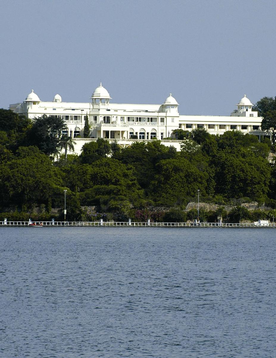 a large white building on a hill next to a body of water at The Lalit Laxmi Vilas Palace in Udaipur