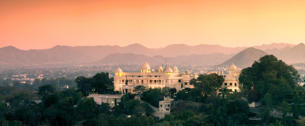 a building on a hill with mountains in the background at The Lalit Laxmi Vilas Palace in Udaipur