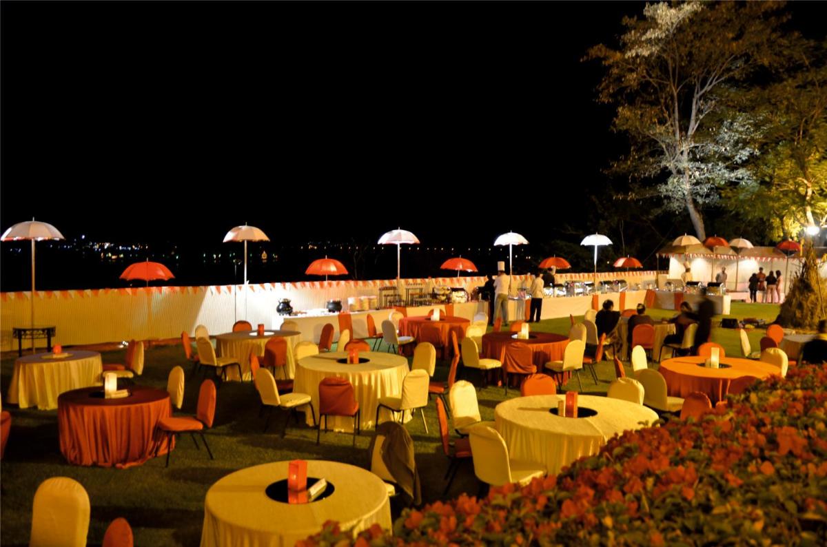 a group of tables and chairs with umbrellas at night at The Lalit Laxmi Vilas Palace in Udaipur