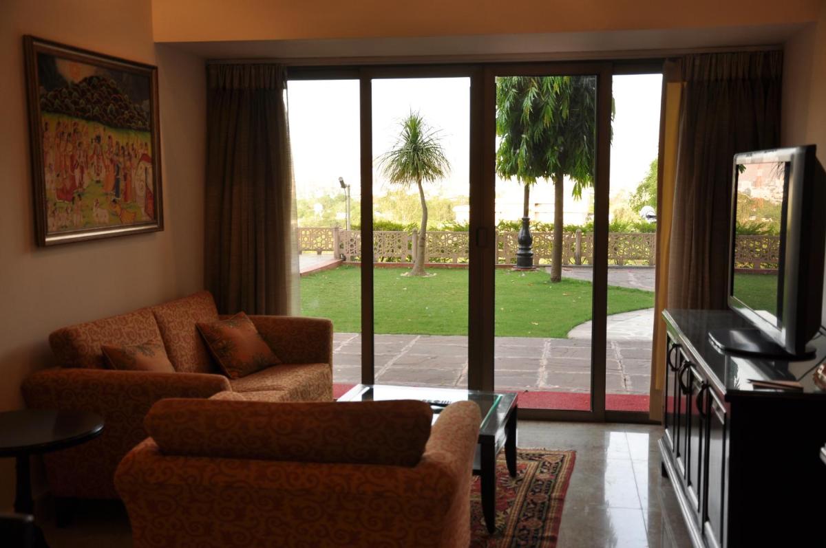 a living room with a couch and chairs and a tv at The Lalit Laxmi Vilas Palace in Udaipur