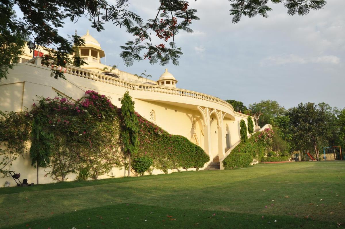 a large white building with a green yard at The Lalit Laxmi Vilas Palace in Udaipur