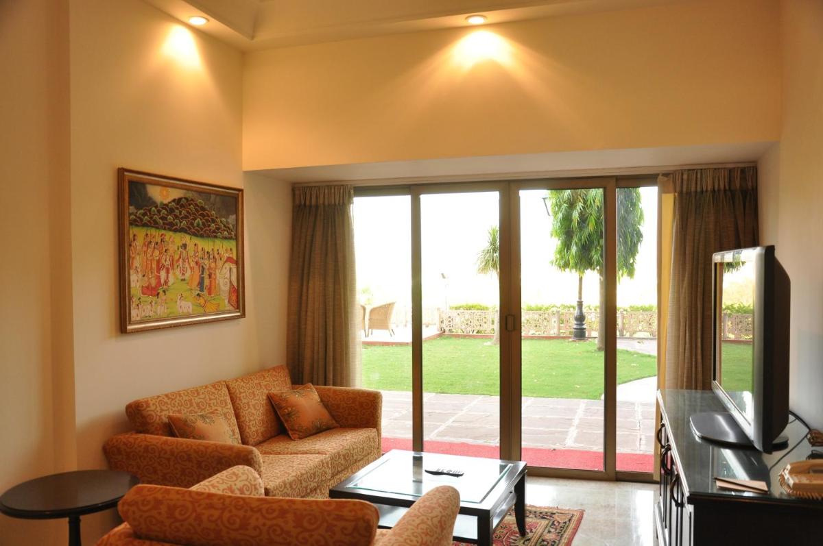 a living room with a couch and a tv at The Lalit Laxmi Vilas Palace in Udaipur