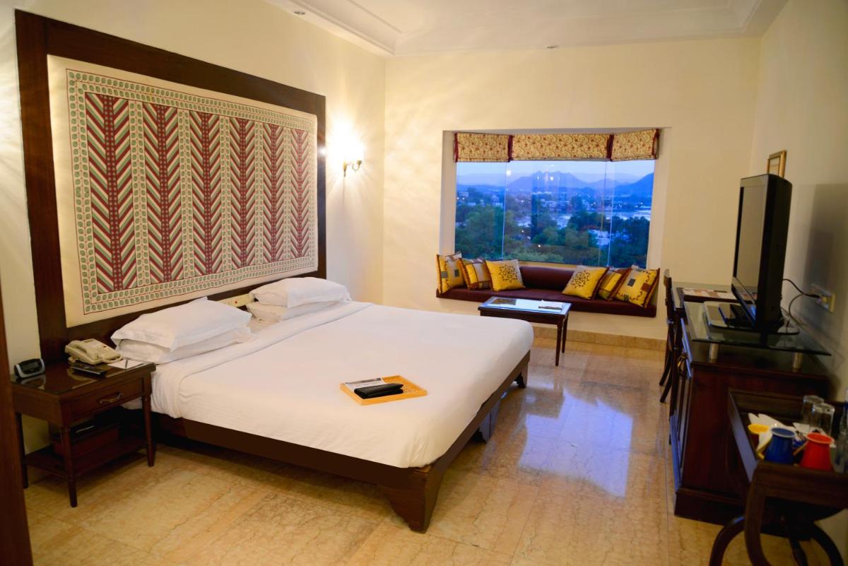 a hotel room with a bed and a television at The Lalit Laxmi Vilas Palace in Udaipur