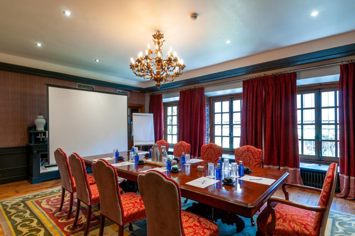Sala de conferencias con mesa, sillas y pantalla de proyección en La Casa del Presidente, en Ávila