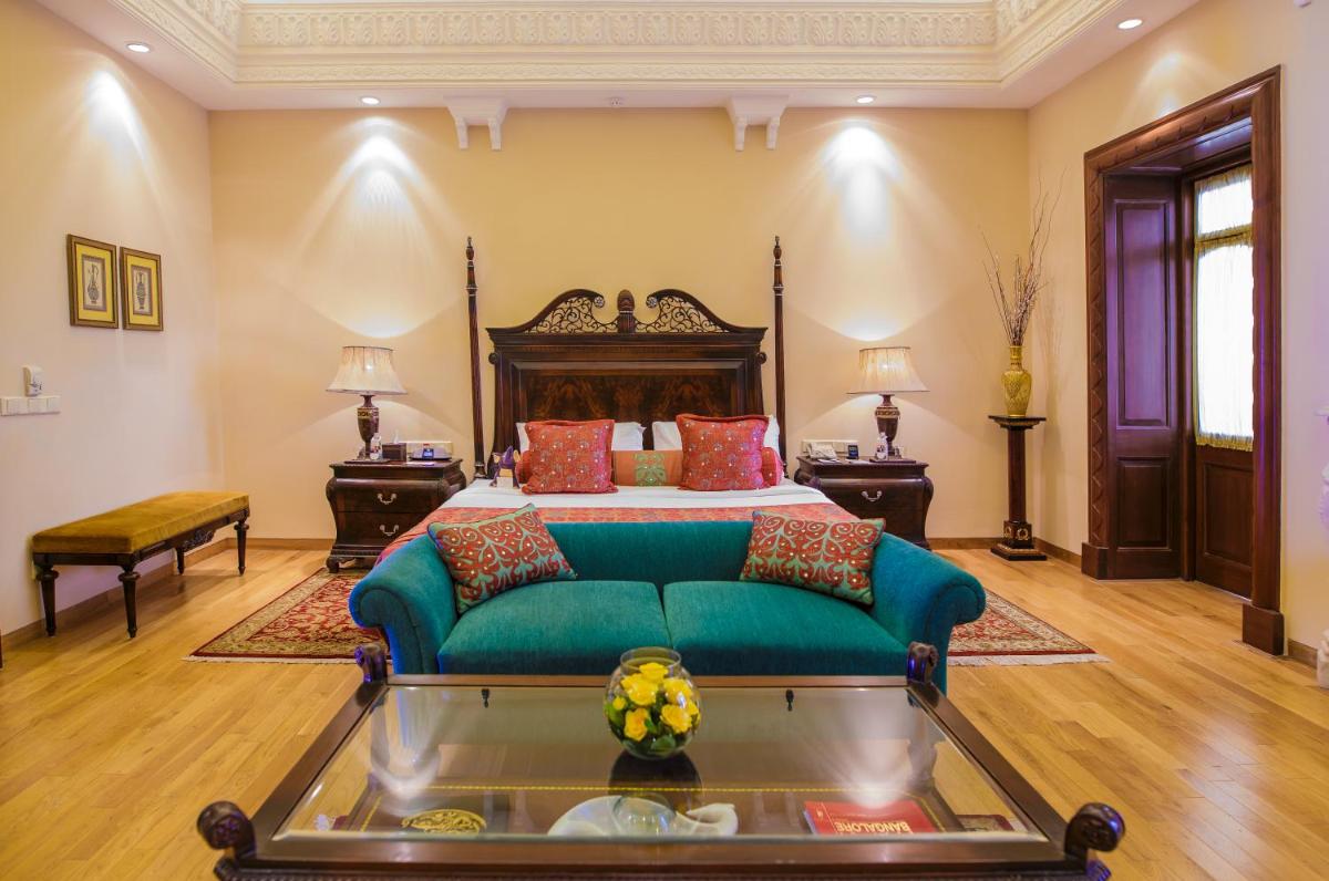 a bedroom with a bed and a green couch at The Lalit Laxmi Vilas Palace in Udaipur